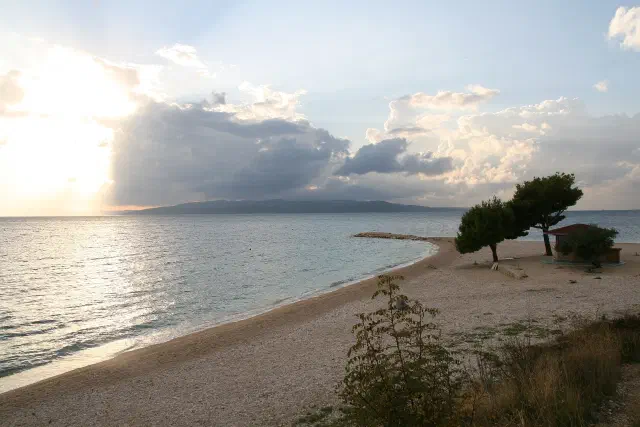 Het lange kiezelstrand van Makarska onder de pijnbomen langs de baai